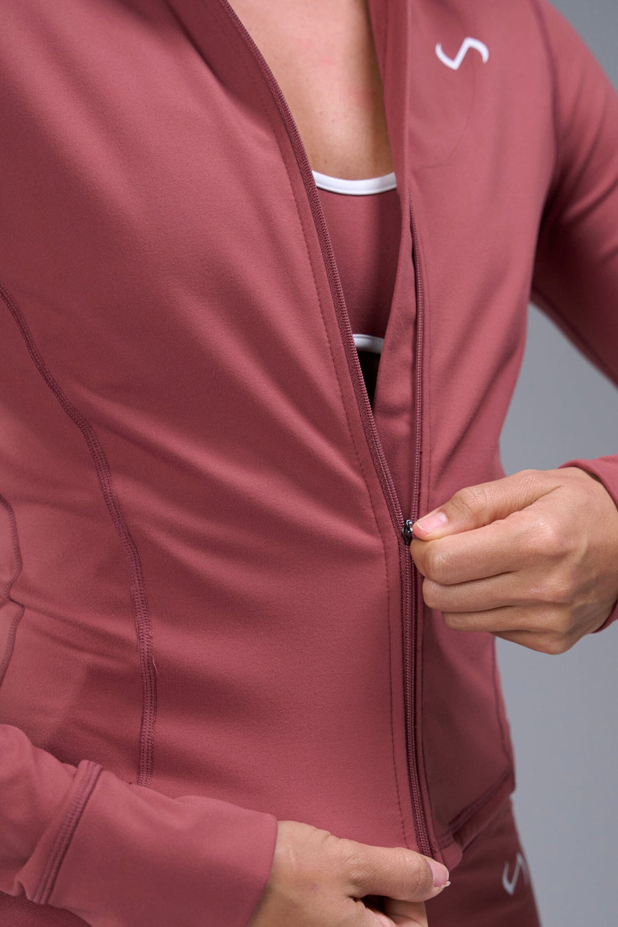 Detail Front View of Orange TLF Tempo Cropped Zip Up Jacket featuring thumbholes and cropped length for gym and lifestyle wear 
