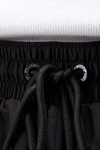 Detail View of Black TLF Track Shorts (Men’s GTS Gym-To-Street Edition) featuring side zipper pockets, mesh lining and reflective piping details.
