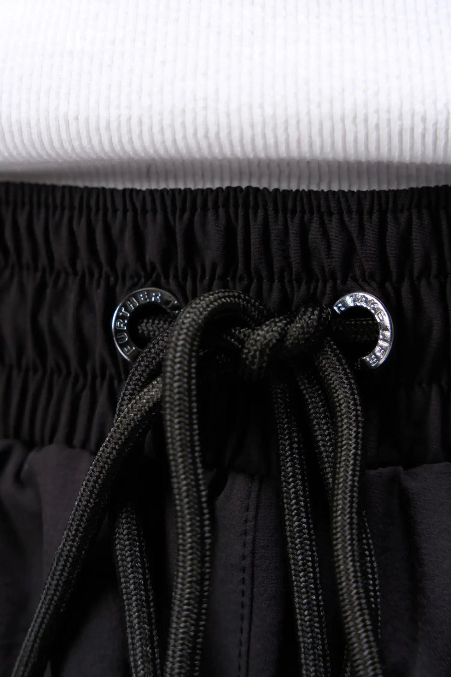 Detail View of Black TLF Track Shorts (Men’s GTS Gym-To-Street Edition) featuring side zipper pockets, mesh lining and reflective piping details.