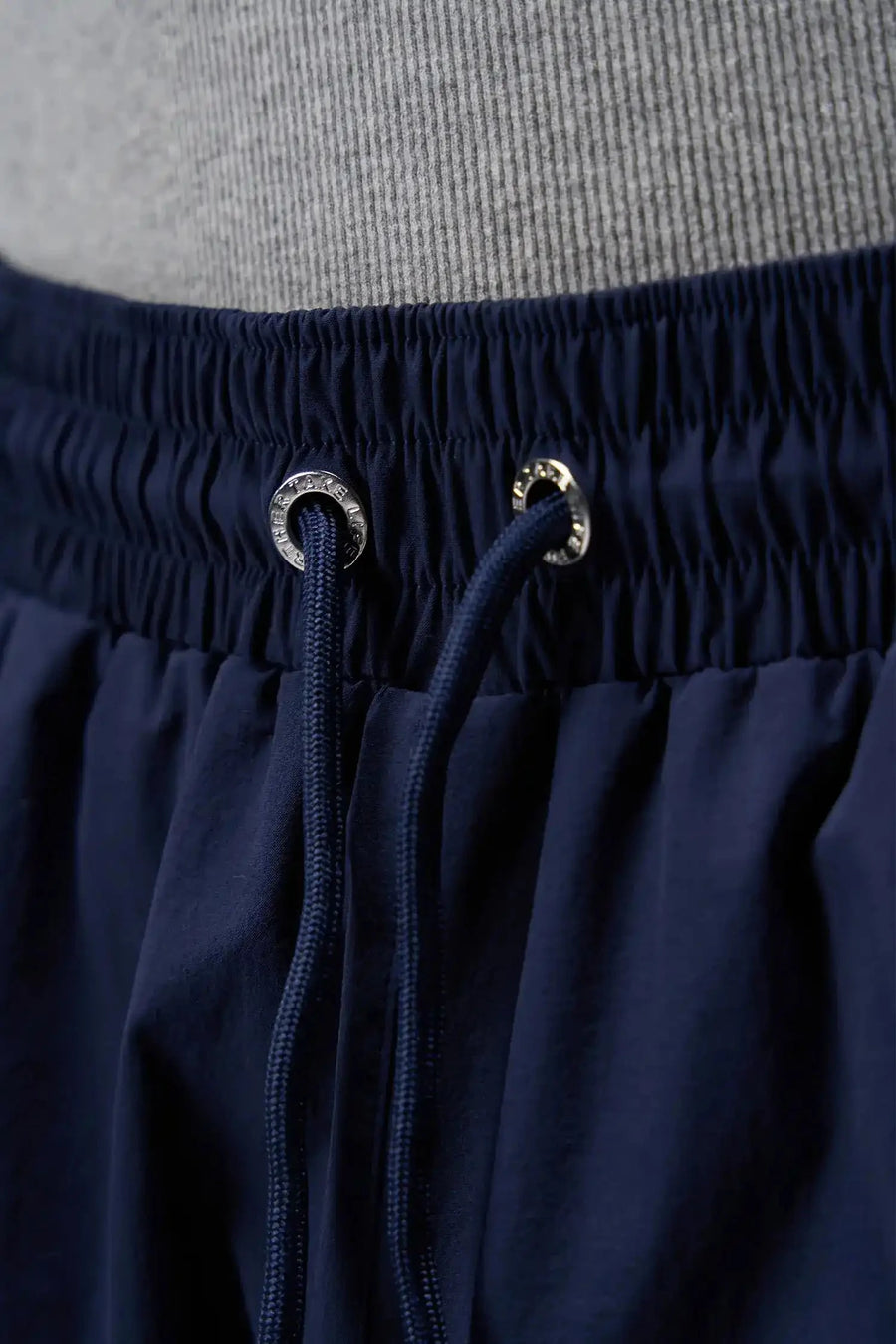 Detail View of Blue TLF Track Shorts (Men’s GTS Gym-To-Street Edition) featuring side zipper pockets, mesh lining and reflective piping details.