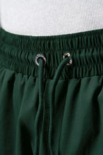 Detail View of Green TLF Track Shorts (Men’s GTS Gym-To-Street Edition) featuring side zipper pockets, mesh lining and reflective piping details.