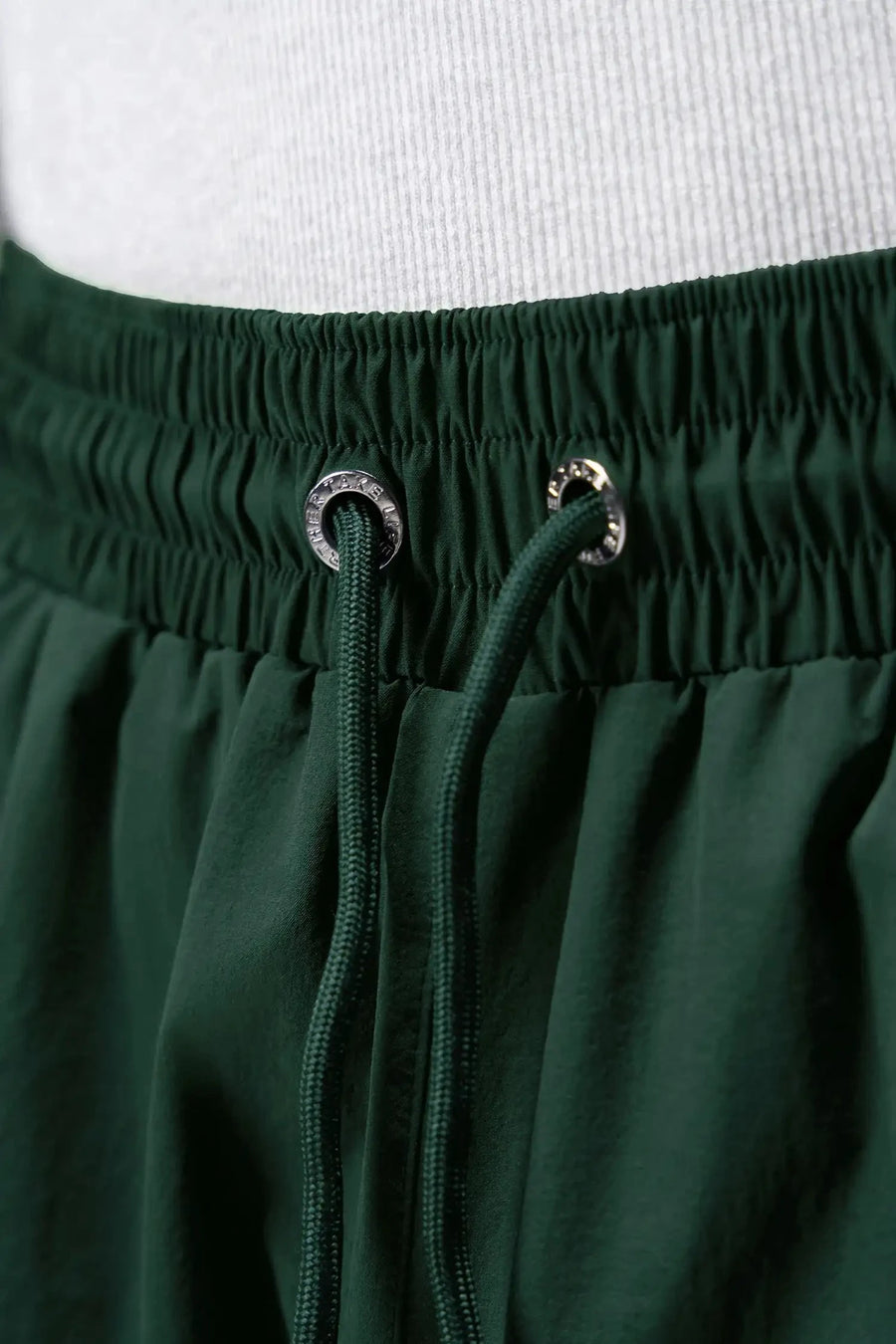 Detail View of Green TLF Track Shorts (Men’s GTS Gym-To-Street Edition) featuring side zipper pockets, mesh lining and reflective piping details.