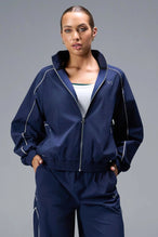 Front View of Blue TLF Track Jacket (Women’s GTS Gym-To-Street Edition) with mesh lining, reflective piping, and premium trims.