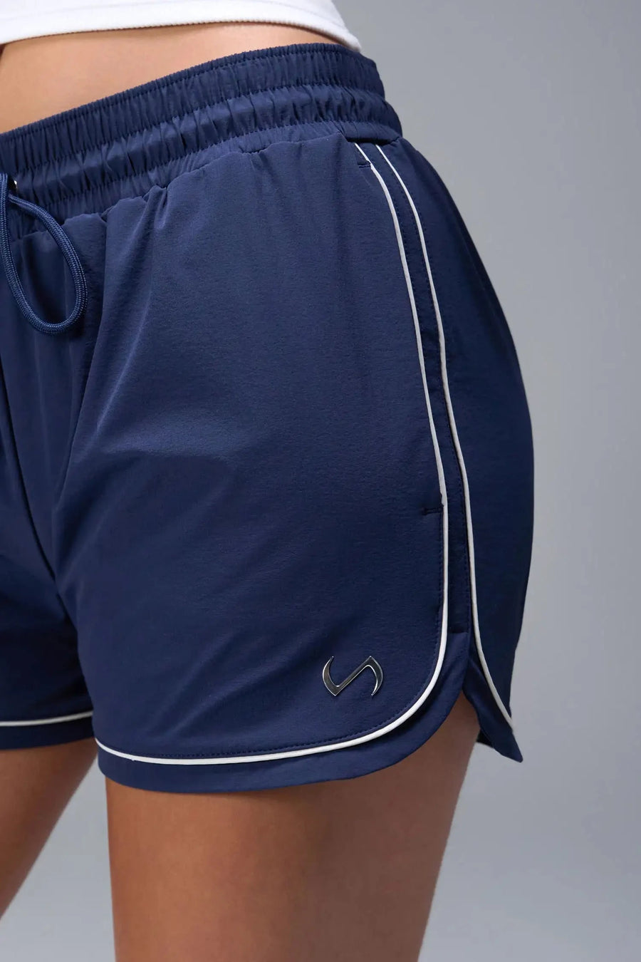 Front View of Blue TLF Track Shorts (Women’s GTS Gym-To-Street Edition) featuring side pockets, mesh lining and reflective piping details.