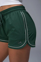 Front View of Green TLF Track Shorts (Women’s GTS Gym-To-Street Edition) featuring side pockets, mesh lining and reflective piping details.