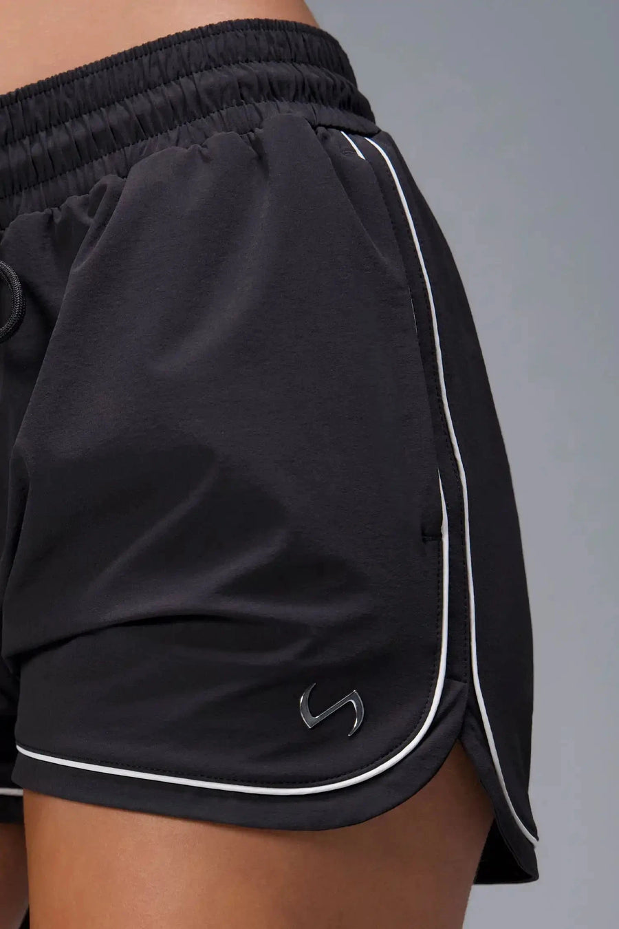 Front View of Black TLF Track Shorts (Women’s GTS Gym-To-Street Edition) featuring side pockets, mesh lining and reflective piping details.