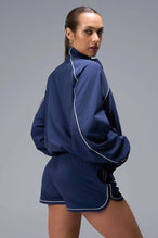 Back View of Blue TLF Track Shorts (Women’s GTS Gym-To-Street Edition) featuring side pockets, mesh lining and reflective piping details.