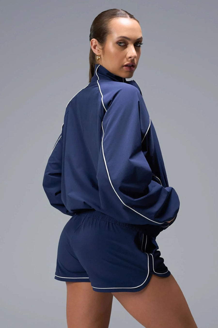 Back View of Blue TLF Track Shorts (Women’s GTS Gym-To-Street Edition) featuring side pockets, mesh lining and reflective piping details.