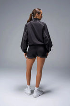 Back View of Black TLF Track Shorts (Women’s GTS Gym-To-Street Edition) featuring side pockets, mesh lining and reflective piping details.
