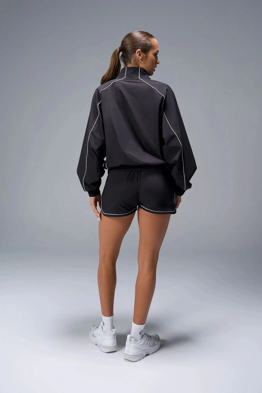 Back View of Black TLF Track Shorts (Women’s GTS Gym-To-Street Edition) featuring side pockets, mesh lining and reflective piping details.