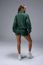 Back View of Green TLF Track Shorts (Women’s GTS Gym-To-Street Edition) featuring side pockets, mesh lining and reflective piping details.