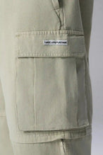 Detail Front View of Green the TLF Zip off cargo pants featuring side cargo pockets and a zip off design that transforms them into shorts